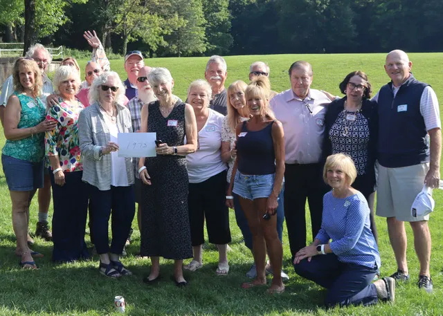 18 older adults from the class of 1973 posting for a group shot