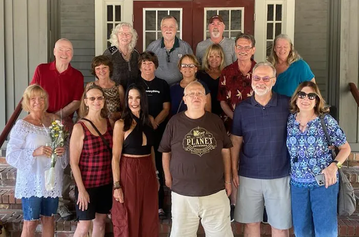 16 older adults standing on steps for a reunion group shot