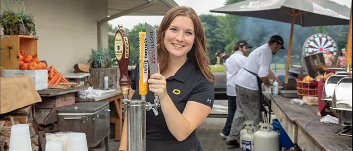 Black Bear Golf employee pouring a glass of beer